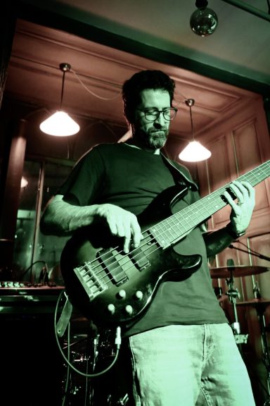 Bassist bei einem Live-Konzert  im Sir Capulus in Füssen, spielt E-Bass auf der Bühne, stimmungsvolle Baratmosphäre im Allgäu. 