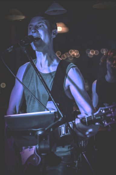 Sänger mit E-Gitarre bei einem Live-Konzert im Sir Capulus in Füssen, Bühnenlicht und Konzertstimmung in der Bard im Allgäu.